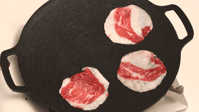 Raw beef slices on a hot grill pan