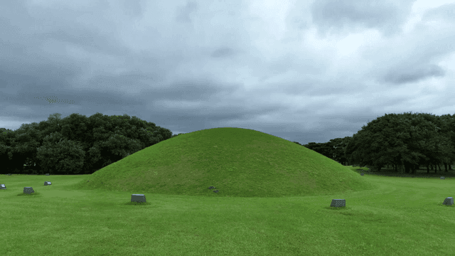 Green burial mounds under cloudy skies