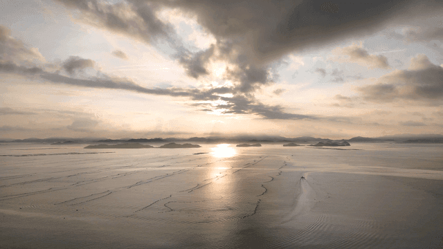 Sunset over calm sea with island visible in distance