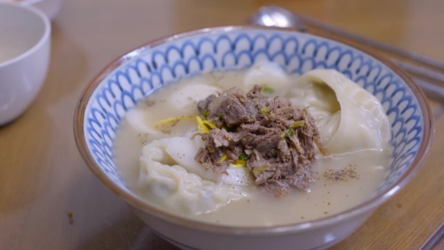 A bowl of Korean sliced rice cake and mandu soup with beef