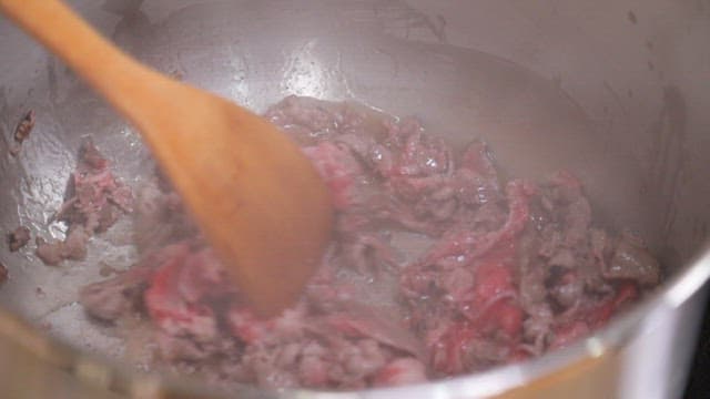 Stirring beef slices in a pot