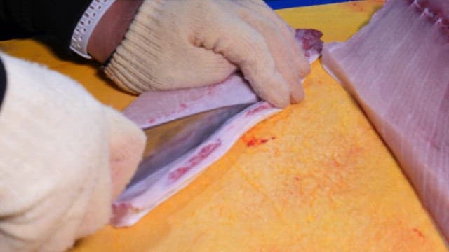 Slicing fresh yellow tail on a cutting board