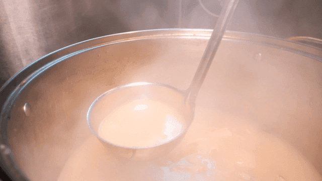 Chef scooping up steaming hot soup