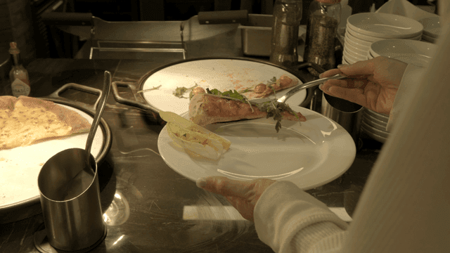Person serving pizza and salad on plates at buffet