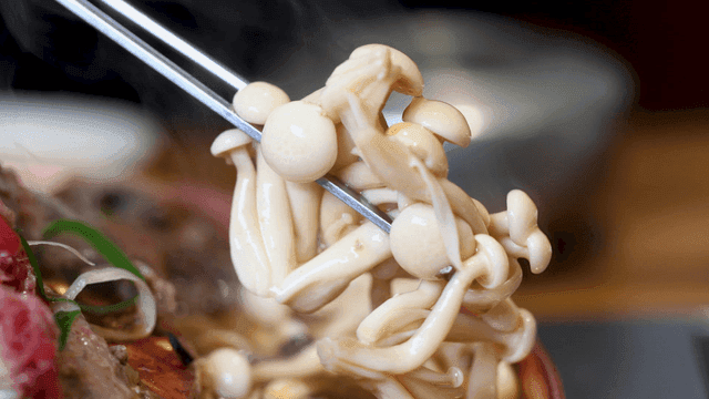 Chopsticks picking up mushroom bulgogi hot pot