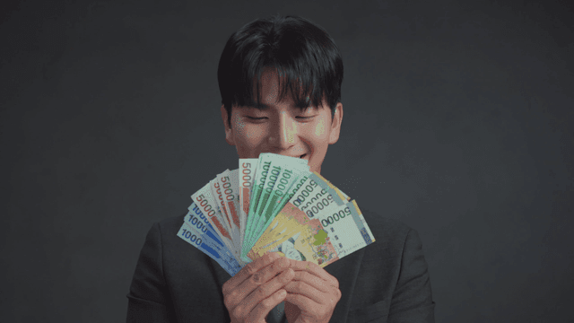 미소를 지으며 한국 지폐를 들고 있는 남자