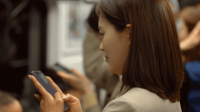 Female office worker looking at her phone on subway