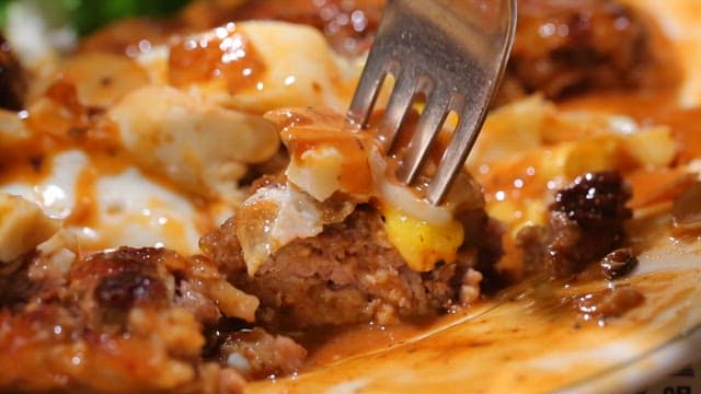 Fork lifting a piece of juicy hamburger steak