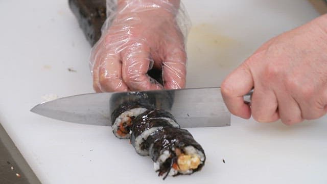 도마 위에서 김밥을 써는 손