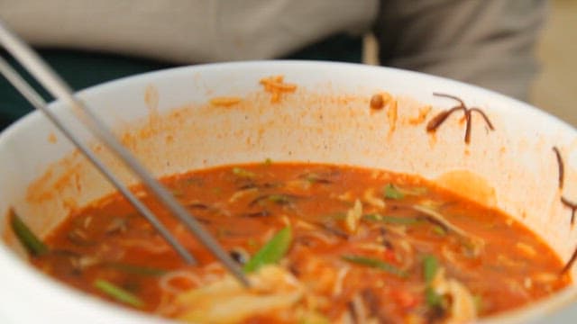 소면을 넣은 물회를 젓가락으로 집어올리는 장면