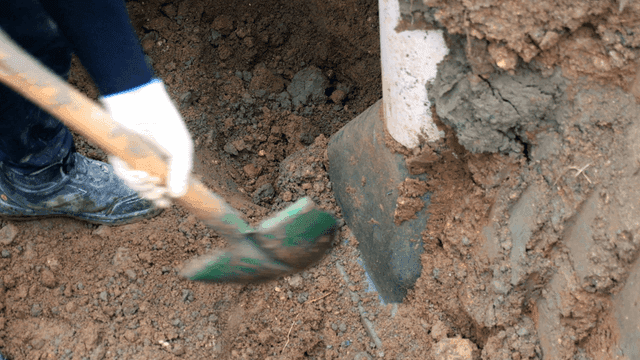 파이프 근처에서 흙을 파는 작업자