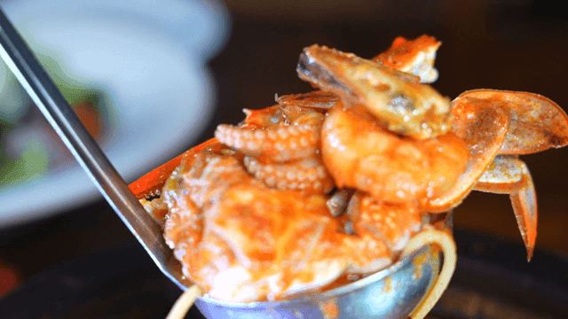 Seafood pasta with rich tomato sauce, ladleful full of it