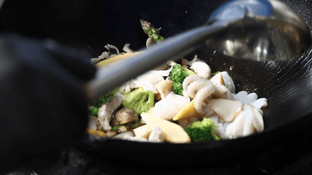 Vegetables and seafood poured into wok