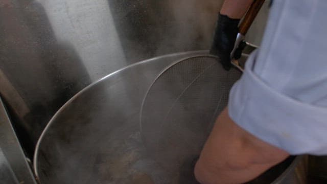 잘 삶아진 고기를 체로 건져 차가운 물에 식히는 모습