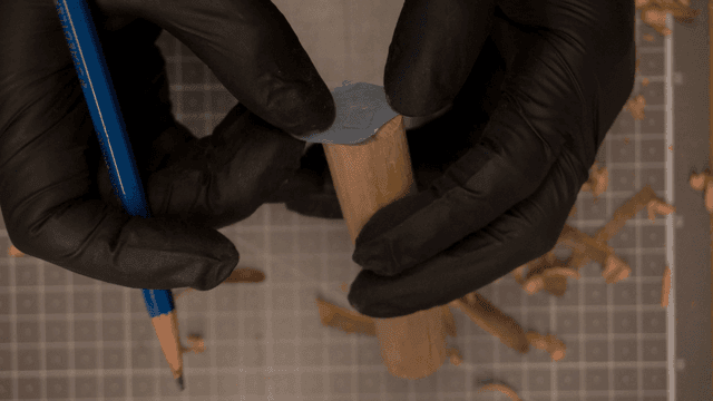 연필로 부품들을 제단하는 장갑 낀 손