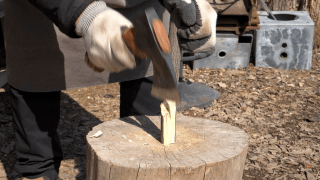 야외에서 도끼로 나무를 다듬는 목공예가