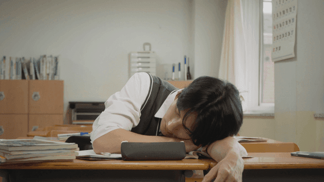 Student sleeping on his arm while studying in the classroom