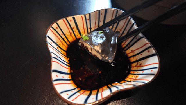 Chopsticks dipping in soy sauce with dim sum