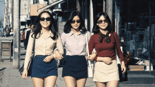 Three women walking together on city street in 70s