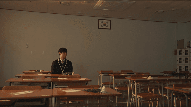 Boy sitting alone in classroom with chrysanthemums