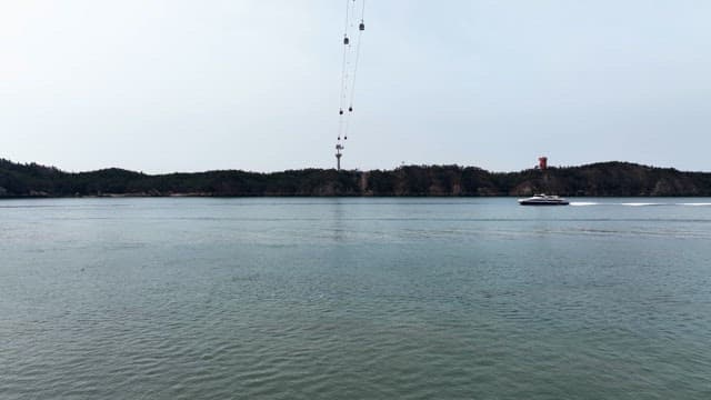 Boat sailing near a cable car over water