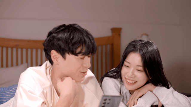 Couple chatting on bed while looking at phone