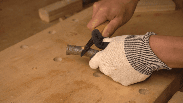 작업대에서 칼로 나무 조각하는 손