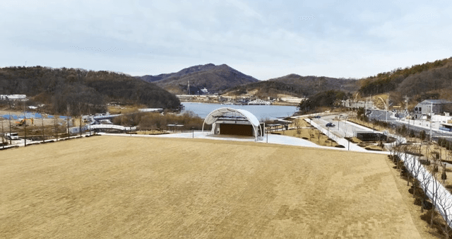 Field with a mountain view behind and an outdoor stage