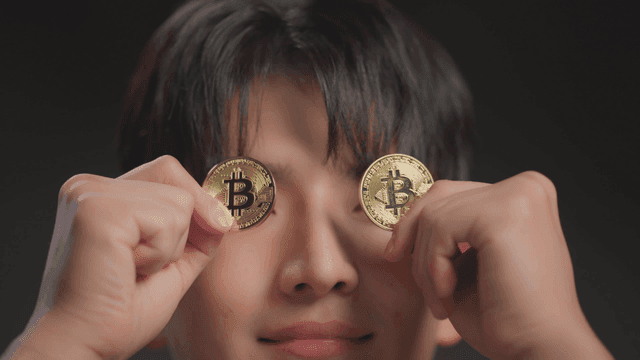 Person holding bitcoins over their eyes