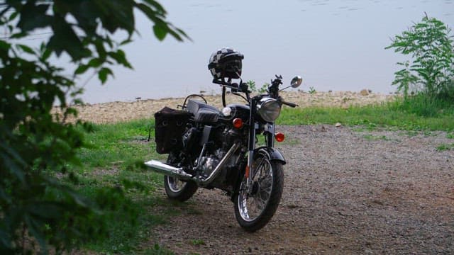 A motorcycle parked by the lakeside on a gravel path.