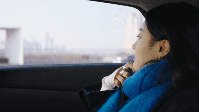 Profile of a woman looking out the taxi window at the road
