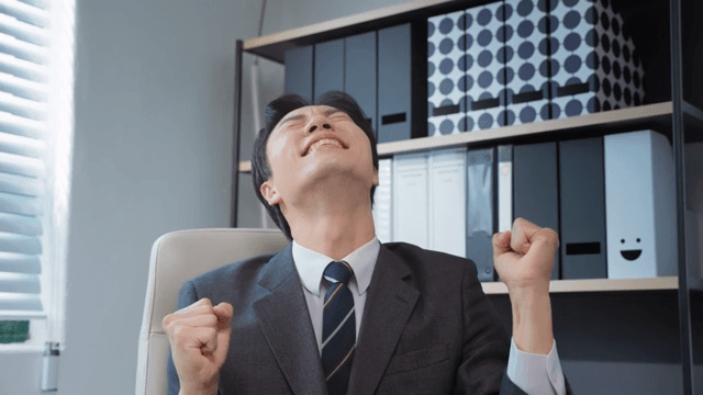 책상에 앉아 환호하는 사업가