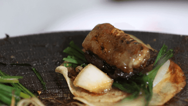 Grilled beef intestines and vegetables on a hot plate