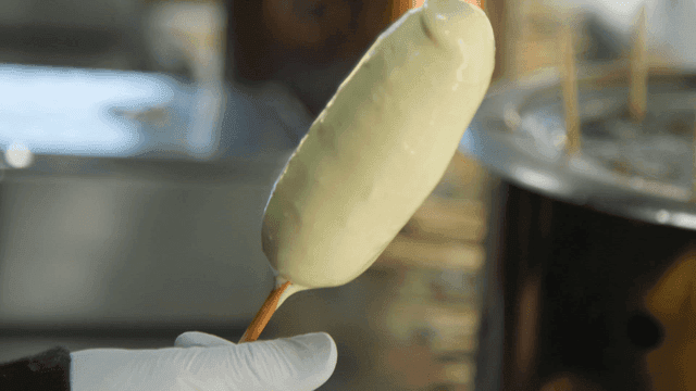 Corn dog being dipped in batter