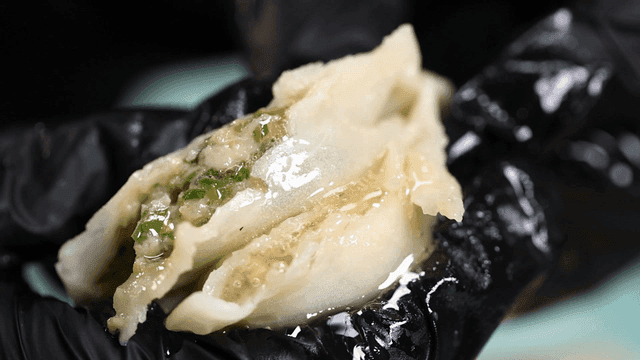 Dumplings pressed by gloved hands, bursting with juice