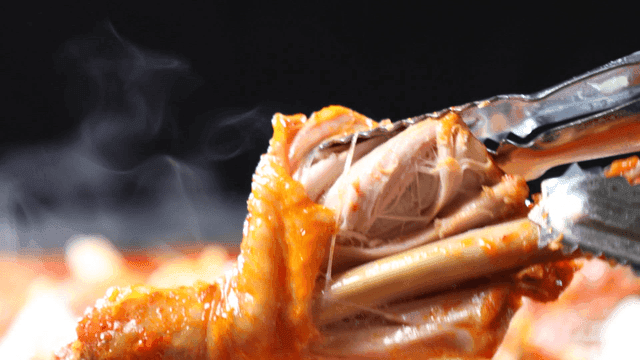 Steaming hot spicy chicken stew, tongs for tearing chicken legs