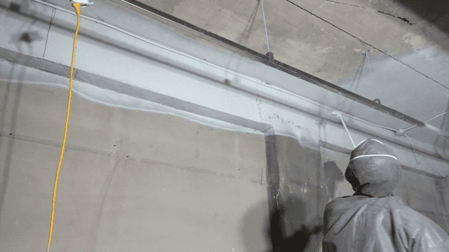 Worker spraying paint on bare concrete