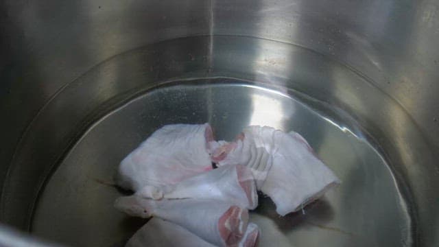 Boiling meat in a large pot with water