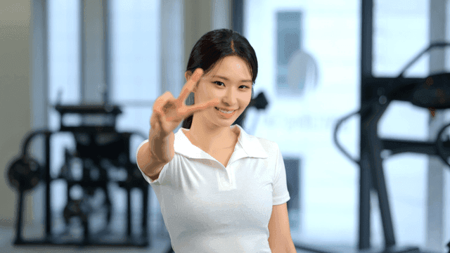 헬스장에서 정면을 보고 브이표시를 하며 미소 짓는 여성