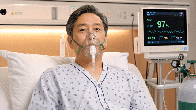 Elderly male patient in bed wearing oxygen mask
