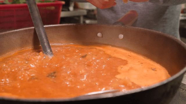 Putting hand-pulled dough into boiling red fish porridge