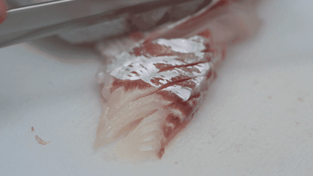 Process of cutting fresh raw fish on cutting board