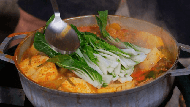 냄비에서 끓고 있는 찌개에 배추 넣기