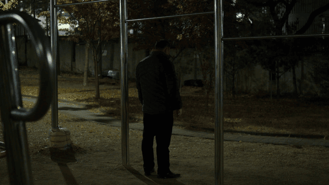 A man exercising on a pull-up bar at night
