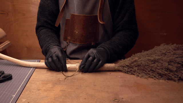 장인이 빗자루 손잡이를 감싸는 모습