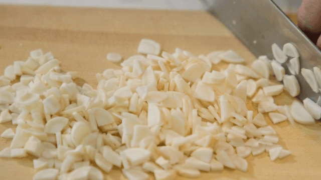 나무 도마 위에서 마늘을 써는 모습