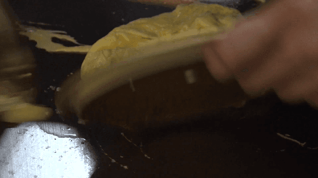 뜨거운 철판에 냄비 뚜껑으로 계란 오믈렛을 만드는 숙련된 요리사