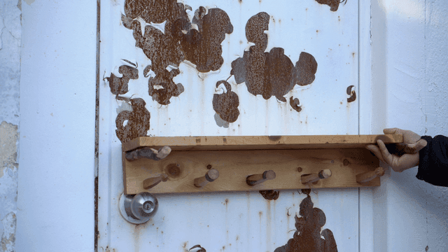 녹슨 문에 나무 거치대를 올려보는 손