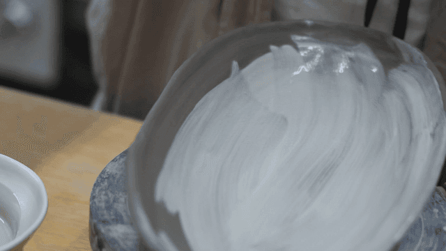 Applying glaze to a pottery bowl