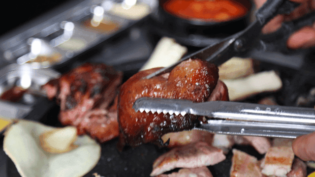 Hands cutting duck meat with scissors